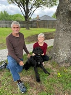 Jim and Robbie Stinnett outside with one of their Goldendoodles